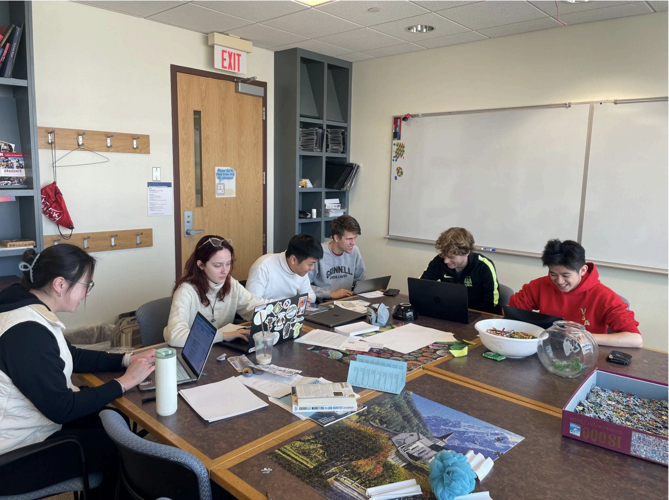 The members of the GrinSync team sit at a table, working together on their paper prototype.